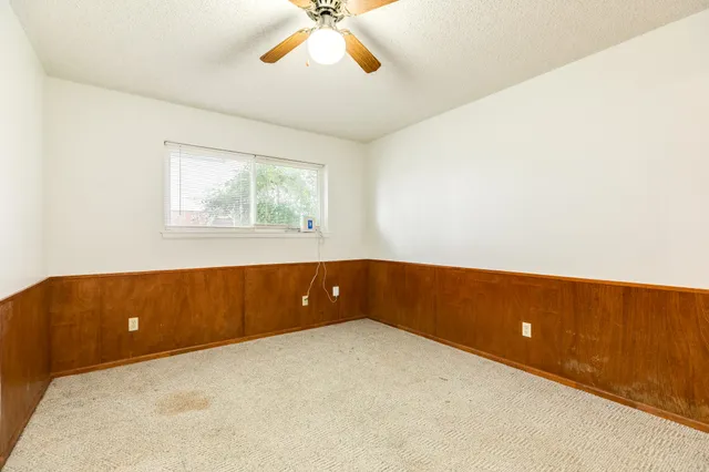 an empty room with windows and ceiling fan