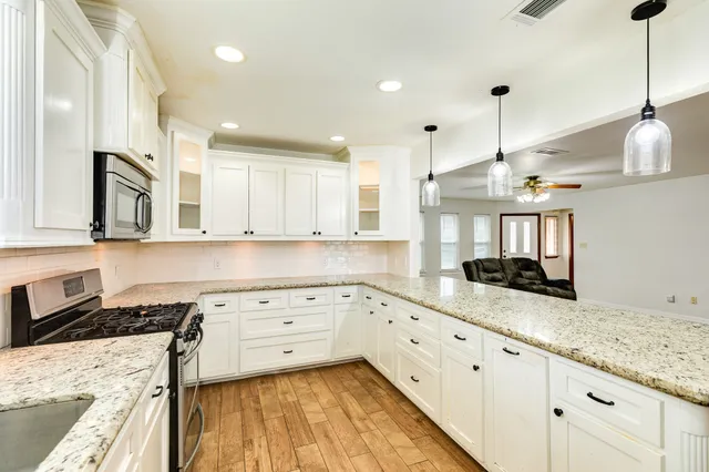 a view of a kitchen with kitchen island a sink wooden floor and a refrigerator