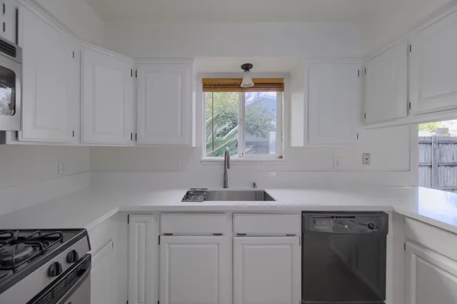 a kitchen with cabinets appliances a sink and a window
