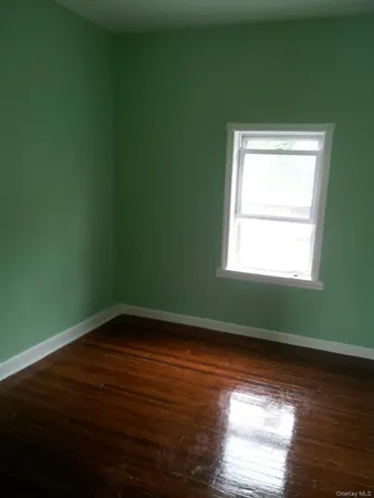a view of a room that has wooden floor and a window