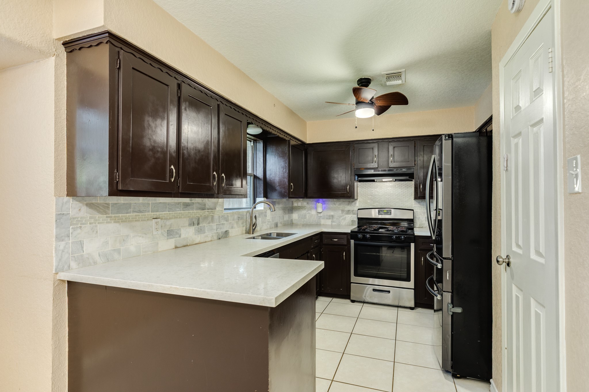 128 Houston Street Angleton, TX 77515 - Photo 10 of 25 a kitchen with stainless steel appliances a sink stove and refrigerator
