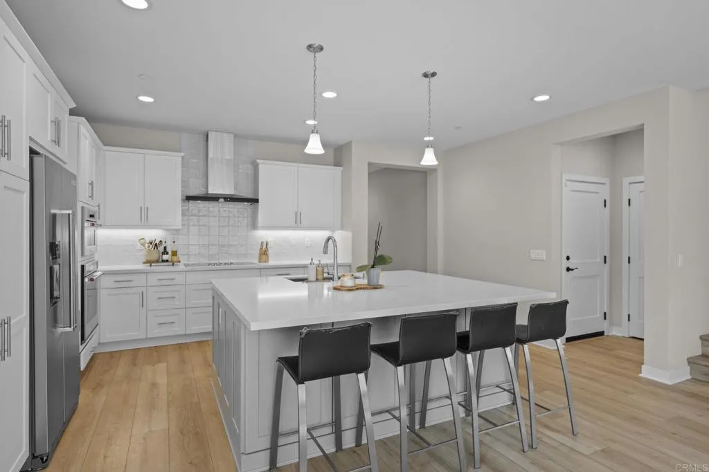3015 Rue De Latour Vista, CA 92084 - Photo 14 of 48 a kitchen with stainless steel appliances kitchen island granite countertop a dining table chairs and white cabinets