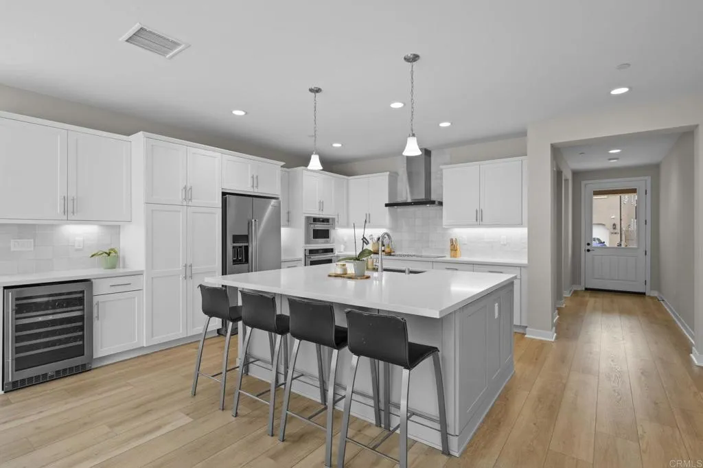 3015 Rue De Latour Vista, CA 92084 - Photo 16 of 48 a kitchen with a sink a stove a refrigerator and island with wooden floor