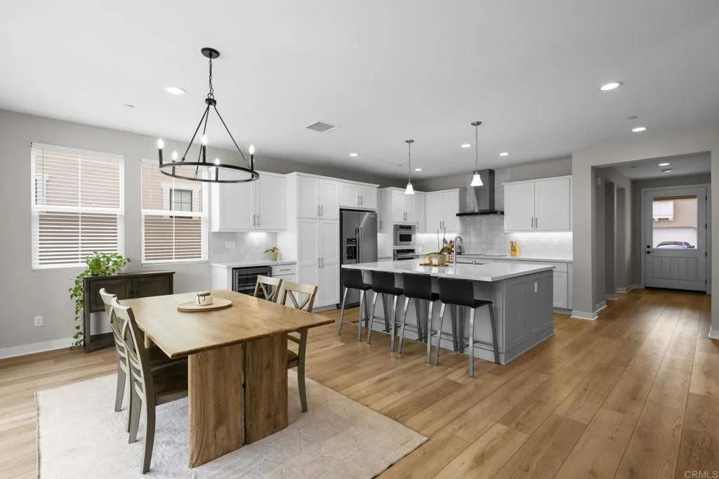 3015 Rue De Latour Vista, CA 92084 - Photo 3 of 48 a kitchen with a dining table chairs wooden floor appliances and cabinets