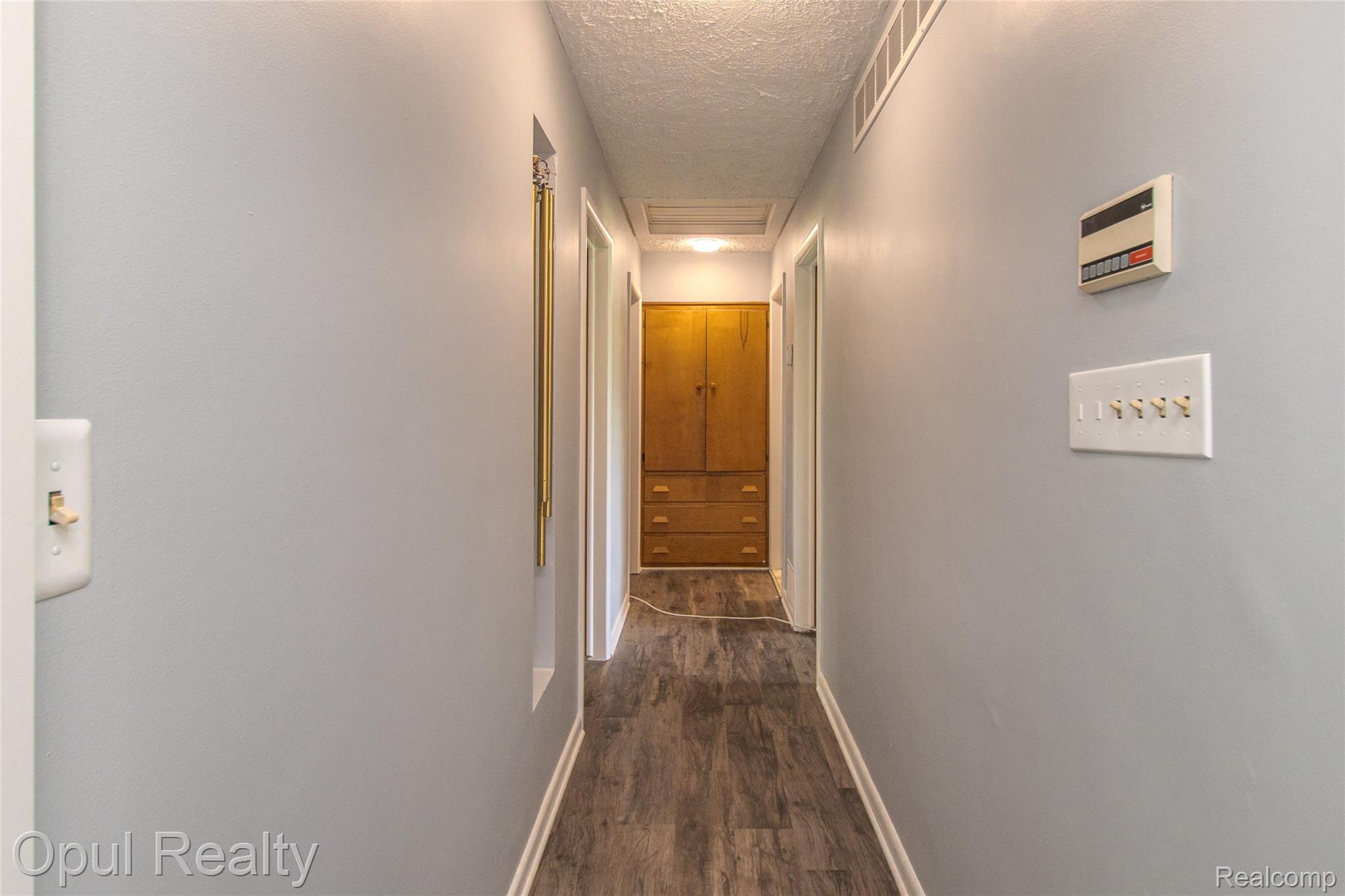 6455 Norham Road Bloomfield Hills, MI 48301 - Photo 47 of 93 Hallway featuring wood-finish flooring, light gray walls, built-in shelving, and a wood-tone cabinet with drawers
