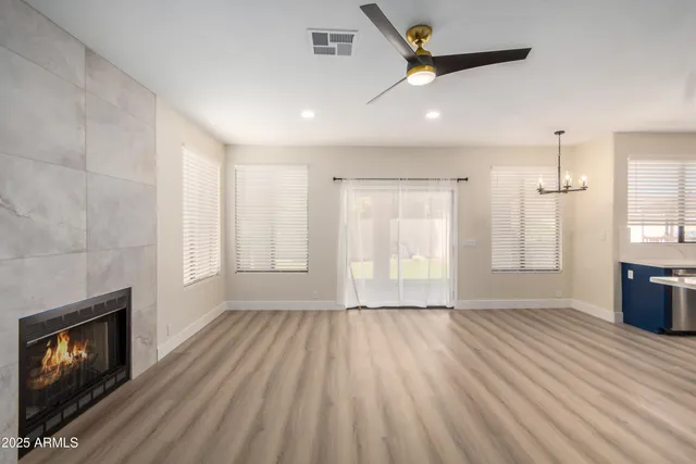 an empty room with wooden floor fireplace and windows