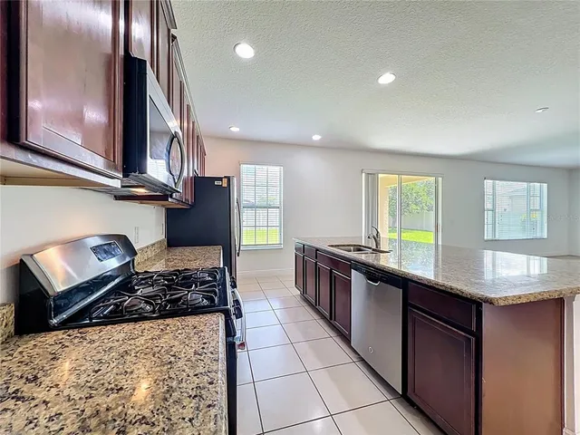 a kitchen with stainless steel appliances granite countertop a stove top oven a sink a granite counter tops and a view of living room