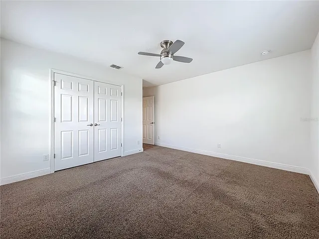 an empty room with windows and ceiling fan