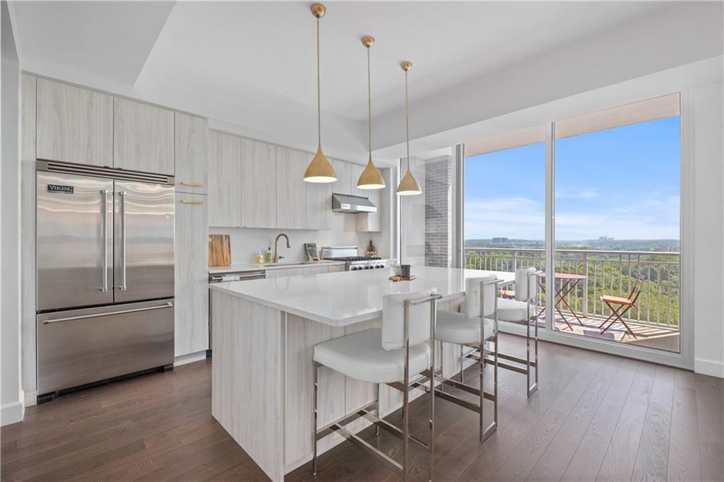 a kitchen with kitchen island a stove a refrigerator a dining table and chairs with wooden floor