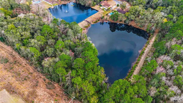 an aerial view of a house with a yard and trees all around