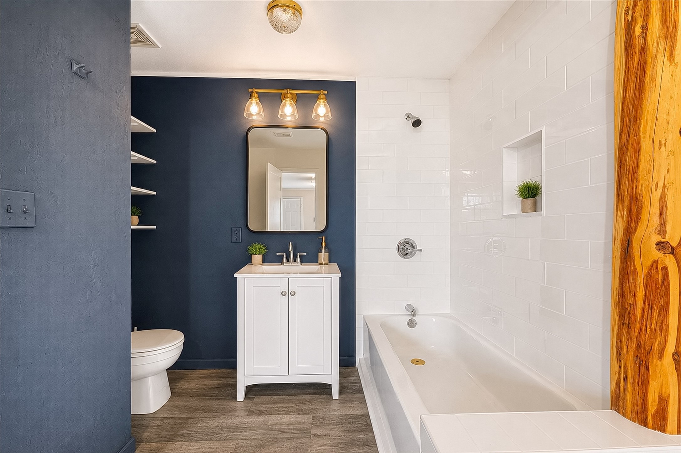 358 Easley Road Smithville, TX 78957 - Photo 19 of 36 Primary bathroom features a single vanity, a modern tub, and sleek white tiling contrasting a bold accent wall.