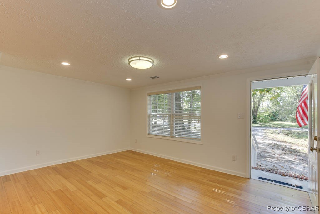 8729 Marlfield Road Gloucester, VA 23061 - Photo 9 of 32 Unfurnished room with a healthy amount of sunlight, a textured ceiling, and light wood-type flooring