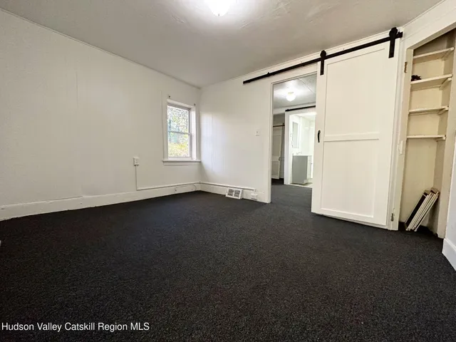 a view of empty room with windows and refrigerator
