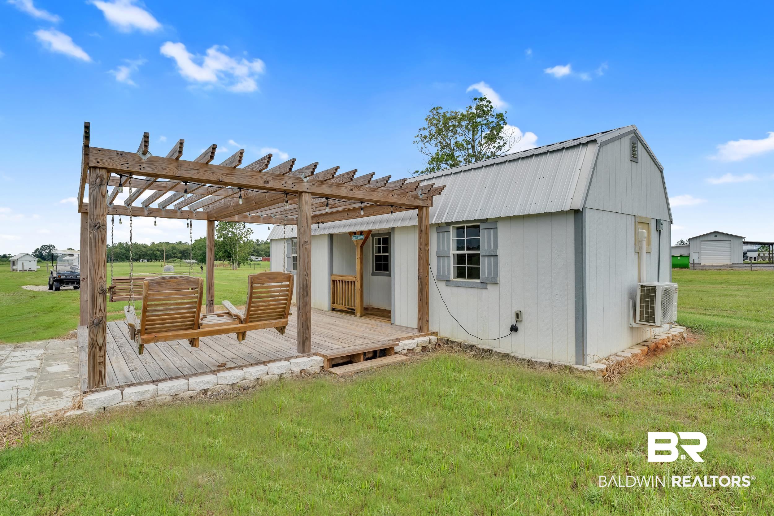22592 Pastoral Lane Foley, AL 36535 - Photo 32 of 45 Rear view of property with a wooden deck, a lawn, a pergola, a gambrel roof, and a metal roof