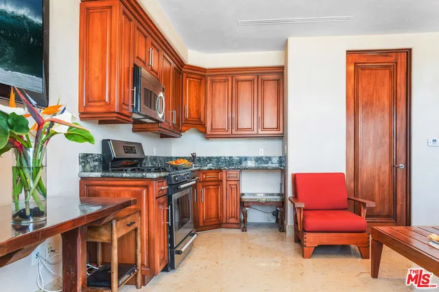 a kitchen with stainless steel appliances granite countertop a table chairs in it and a window