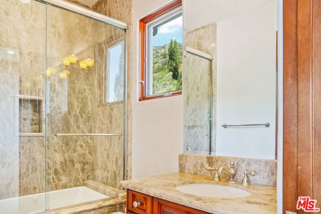 a bathroom with a granite countertop sink a mirror and a shower