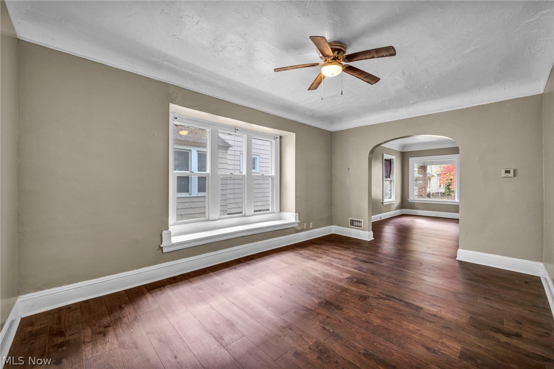 1677 Carlyon Road East Cleveland, OH 44112 - Photo 14 of 41 Unfurnished room featuring dark wood-type flooring, arched walkways, a textured ceiling, and ceiling fan