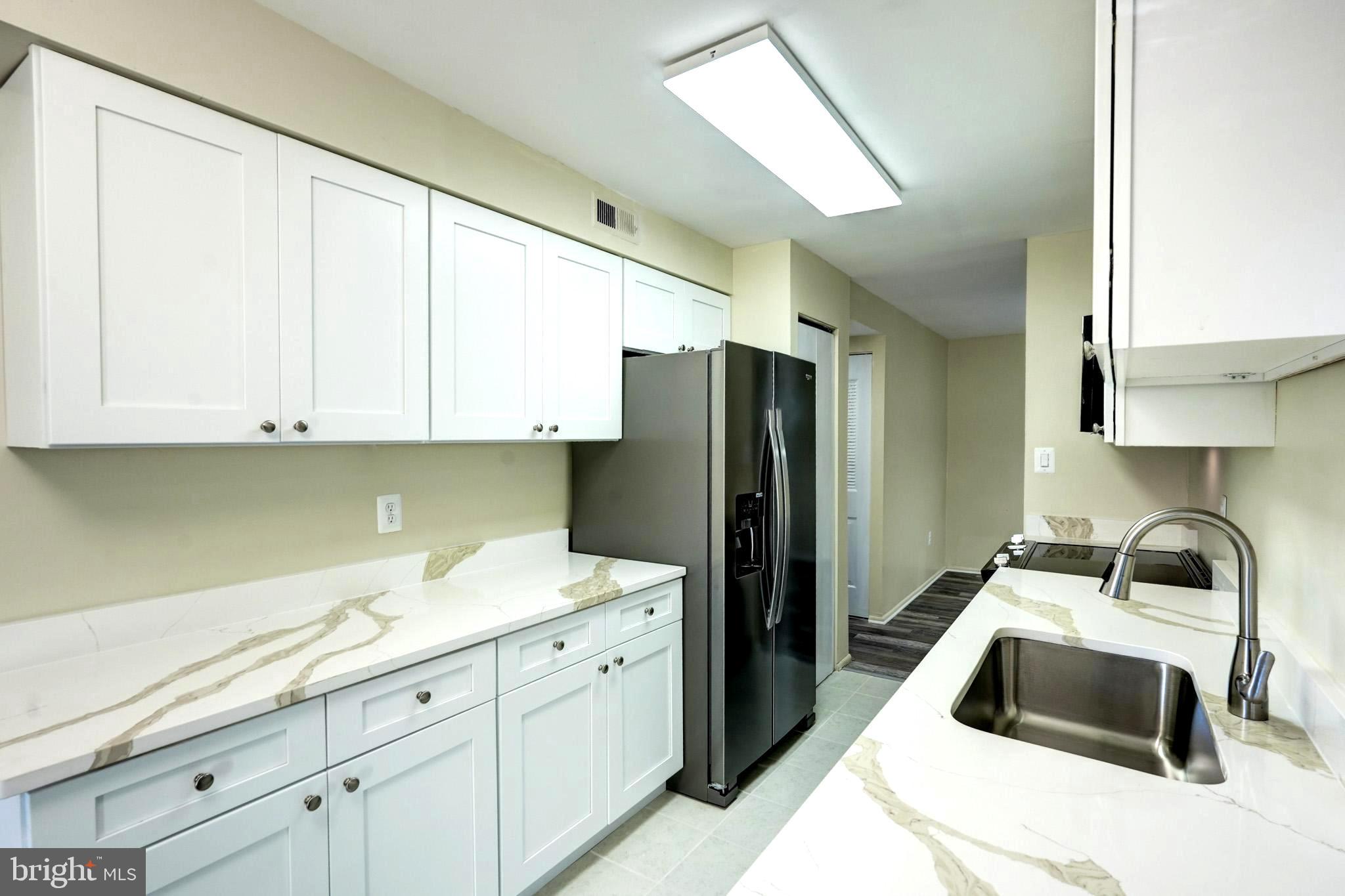 415 Christopher Avenue, Unit 11 Gaithersburg, MD 20879 - Photo 12 of 36 a kitchen with a sink a refrigerator and cabinets