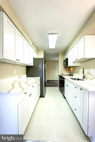 a kitchen with a sink a stove cabinets and wooden floor