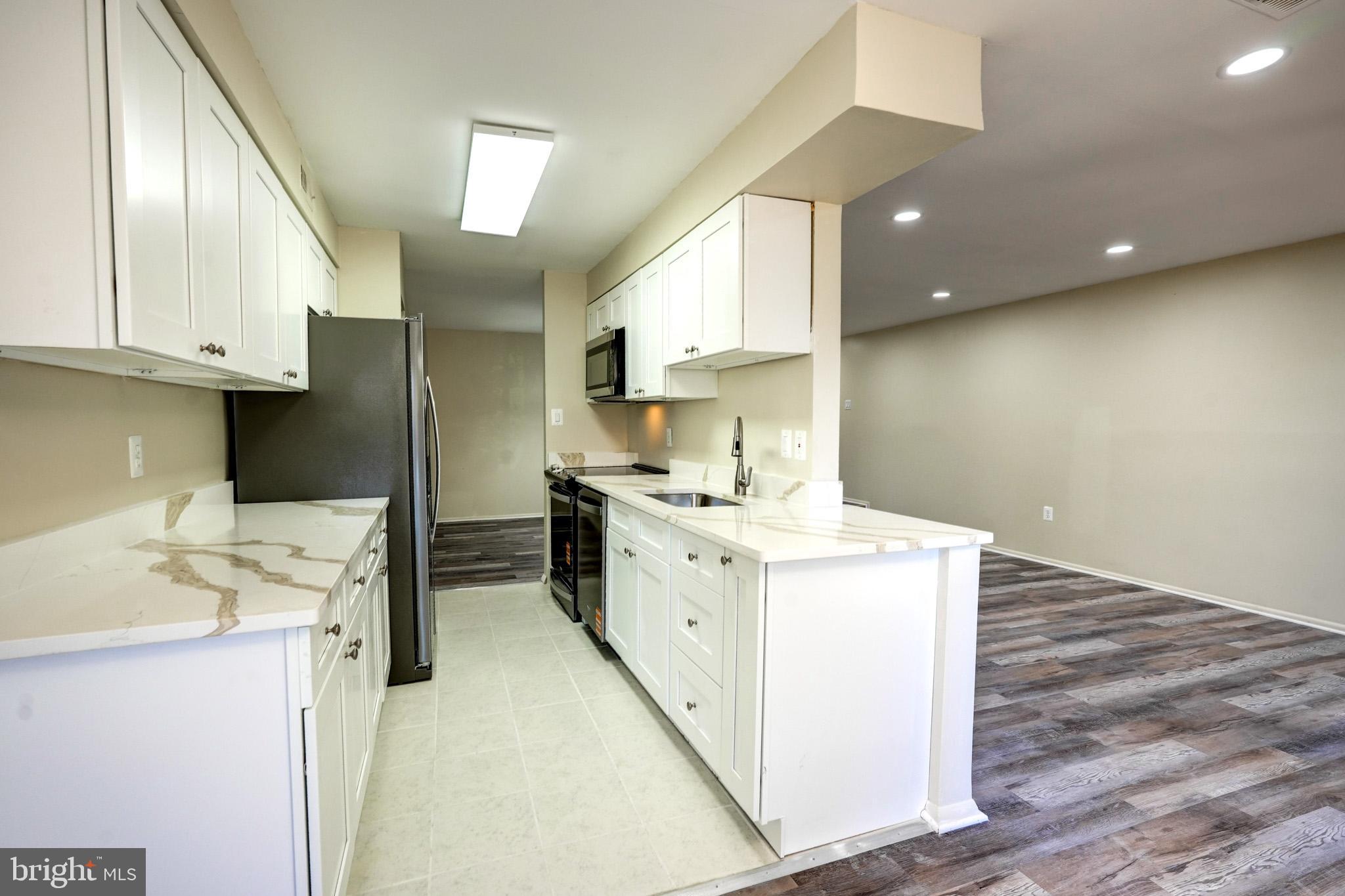 415 Christopher Avenue, Unit 11 Gaithersburg, MD 20879 - Photo 16 of 36 a kitchen with a sink a stove cabinets and wooden floor