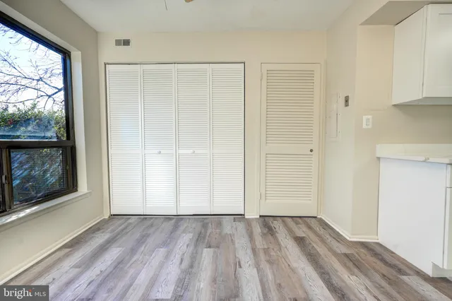 an empty room with wooden floor fan and windows