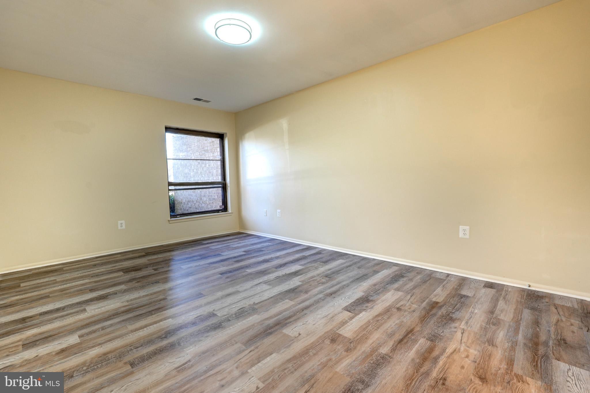 415 Christopher Avenue, Unit 11 Gaithersburg, MD 20879 - Photo 24 of 36 an empty room with wooden floor and windows