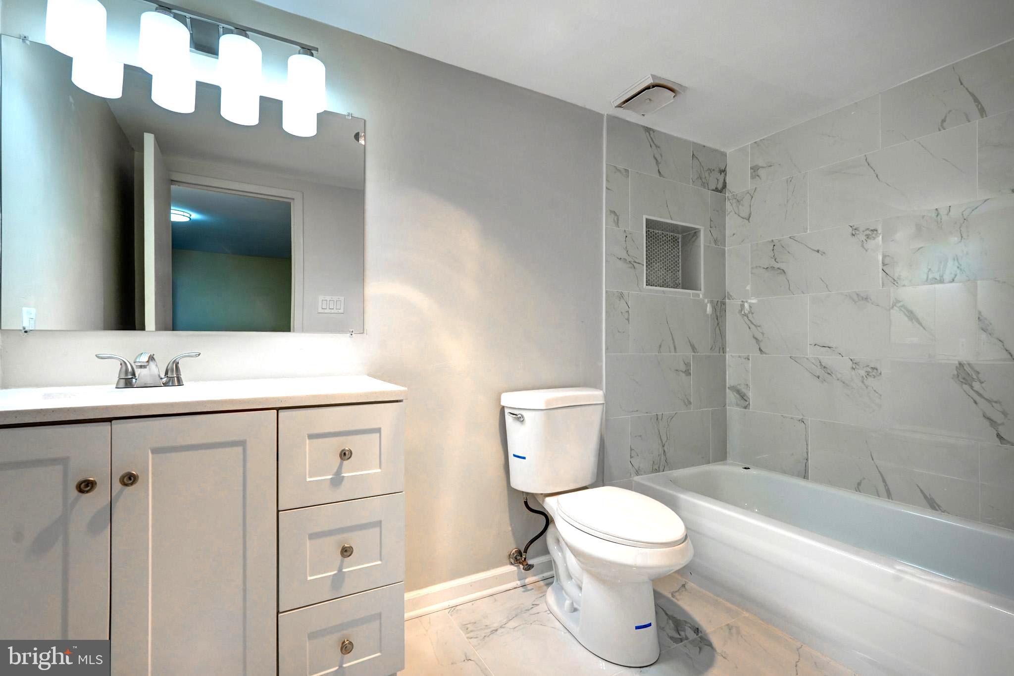 415 Christopher Avenue, Unit 11 Gaithersburg, MD 20879 - Photo 33 of 36 a bathroom with a toilet a sink a mirror a bathtub and vanity