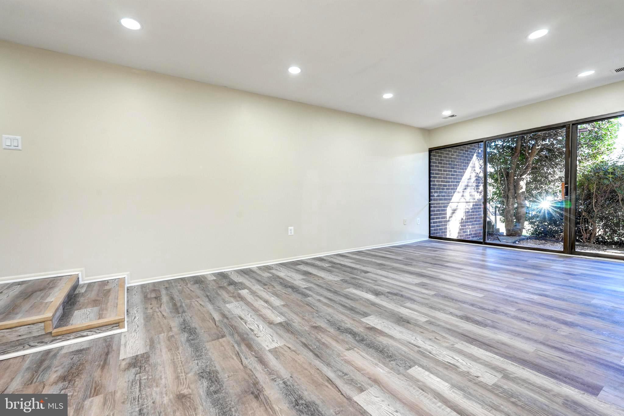 415 Christopher Avenue, Unit 11 Gaithersburg, MD 20879 - Photo 6 of 36 an empty room with wooden floor and windows