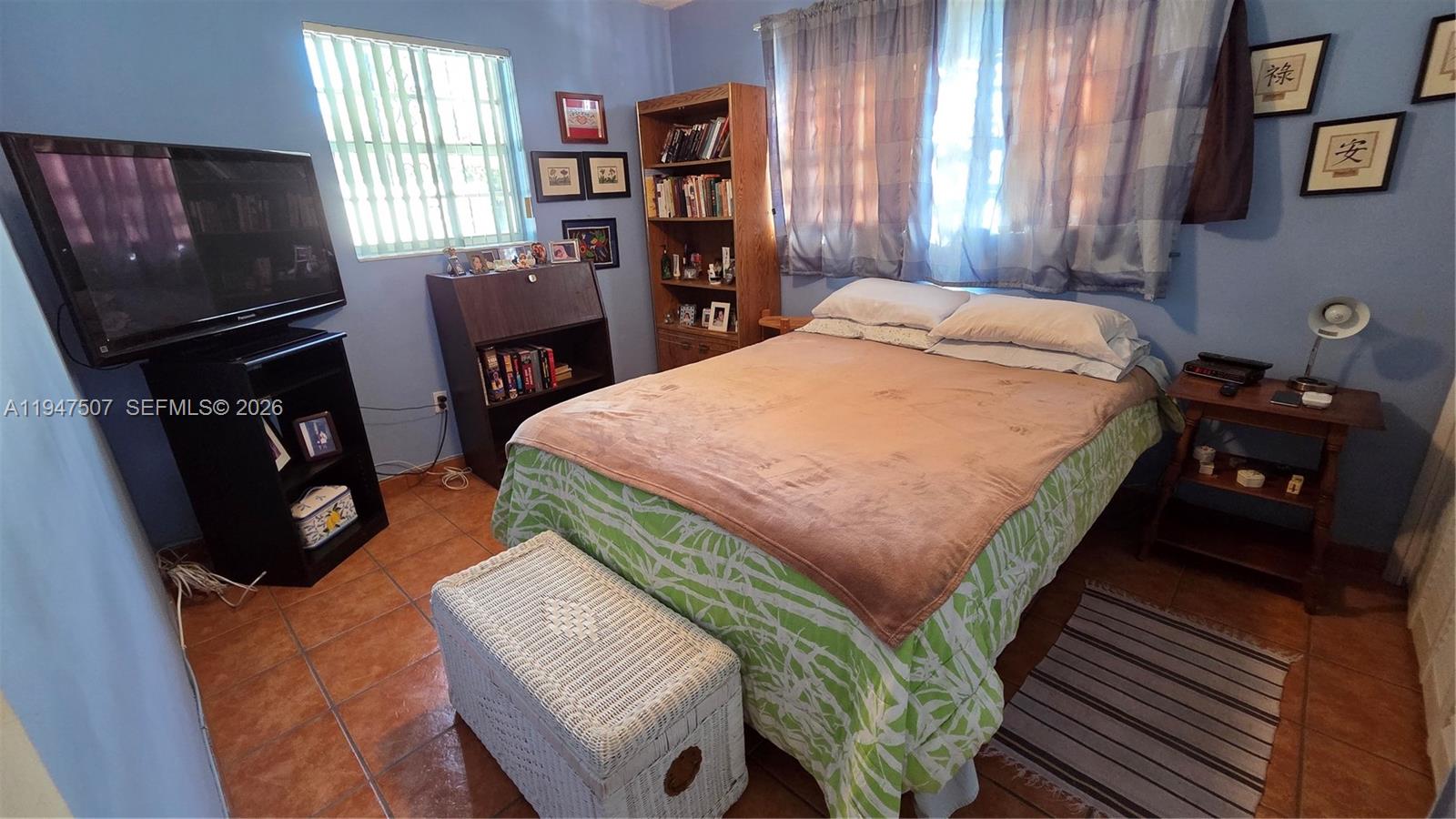 11933 Southwest 196th Terrace Miami, FL 33177 - Photo 19 of 29 a bed sitting in a bedroom next to a window with chair and a flat tv screen