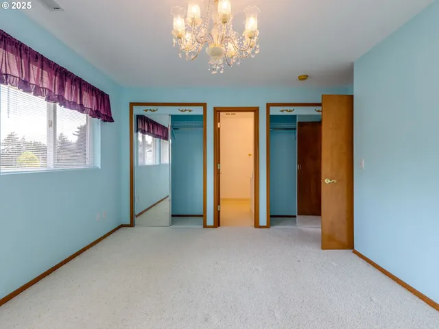 an empty room with chandelier fan and windows