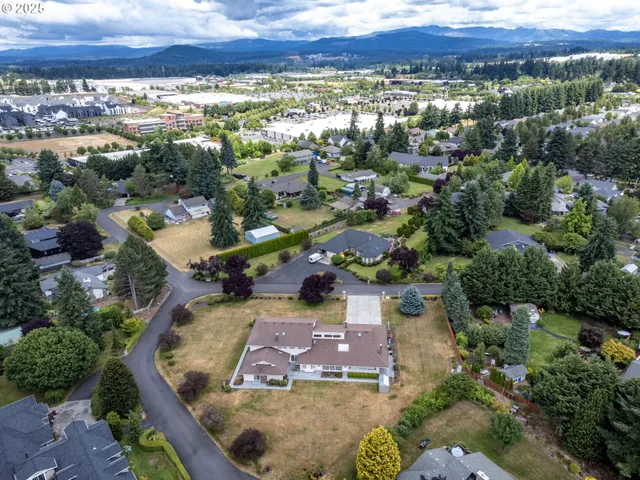 an aerial view of a house with a yard lake and mountain view in back