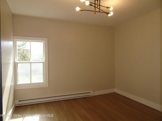 an empty room with wooden floor closet and windows