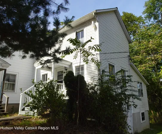 a view of house in front of a big yard with large trees