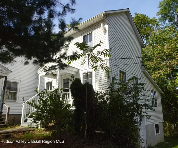 a view of house in front of a big yard with large trees