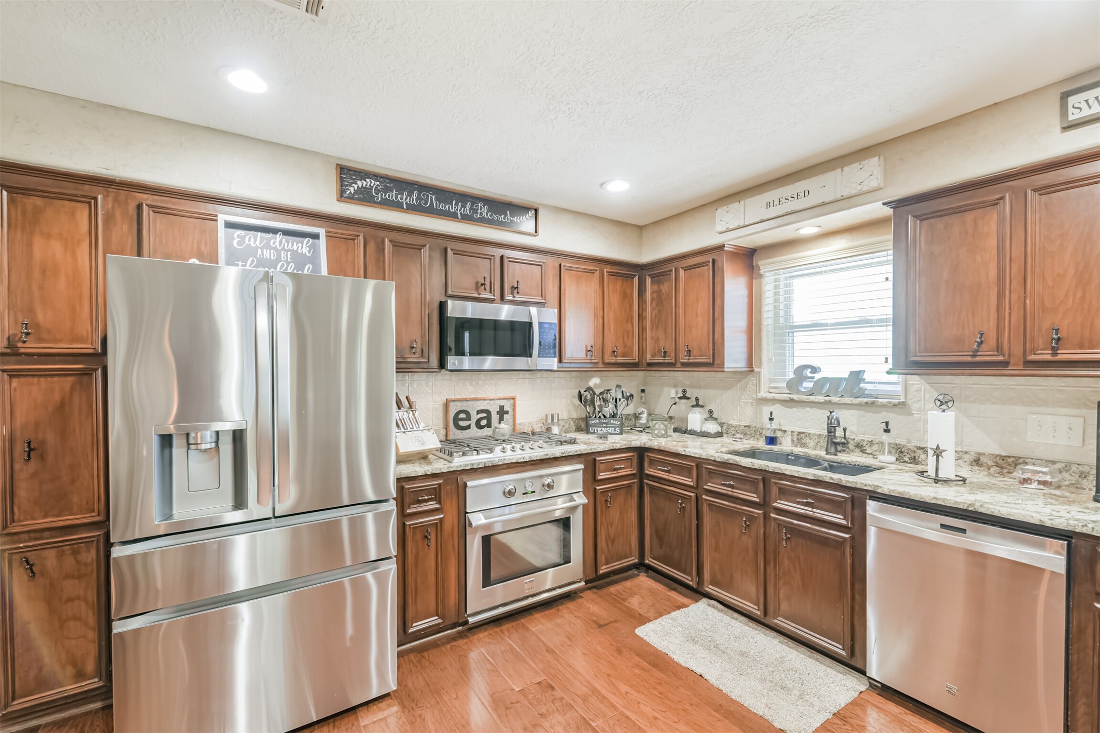 307 West Hufsmith Road Tomball, TX 77375 - Photo 16 of 44 Spacious kitchen with rich wood cabinetry, stainless steel appliances, and elegant granite countertops, offering a warm and inviting atmosphere for cooking and entertaining.