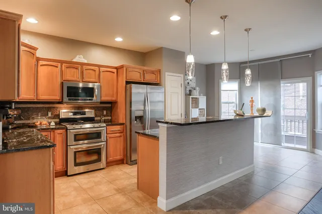 a kitchen with stainless steel appliances granite countertop a refrigerator a stove a sink and a microwave