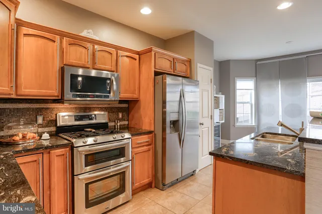 a kitchen with granite countertop a refrigerator stove and microwave