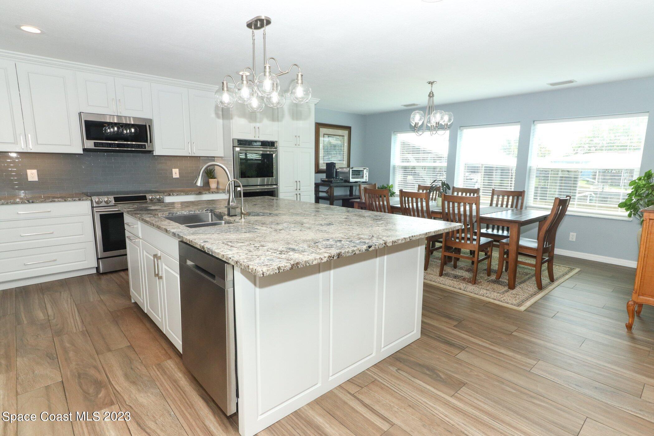 834 Egret Road Cocoa, FL 32926 - Photo 8 of 85 a kitchen with stainless steel appliances granite countertop a stove top oven a sink dishwasher a dining table and chairs with wooden floor