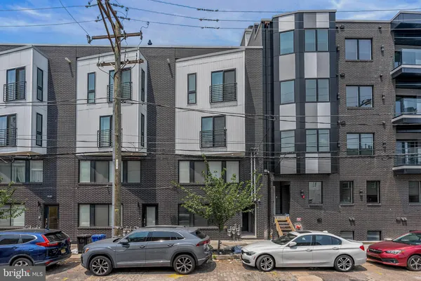 a front view of a residential apartment building with cars parked