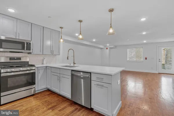 a kitchen with stainless steel appliances granite countertop a sink a stove and a wooden floors