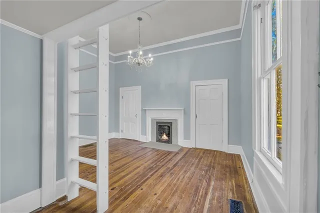 a view of a livingroom with wooden floor a ceiling fan and windows