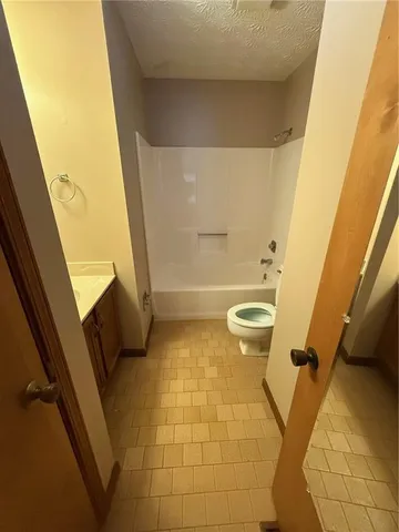 an empty room with a chandelier fan and windows