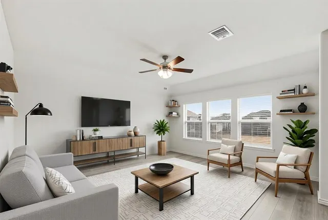 a living room with furniture a flat screen tv and a window