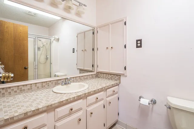 a bathroom with a granite countertop sink a mirror and a shower