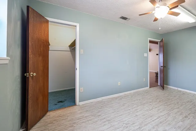 an empty room with closet and a chandelier fan