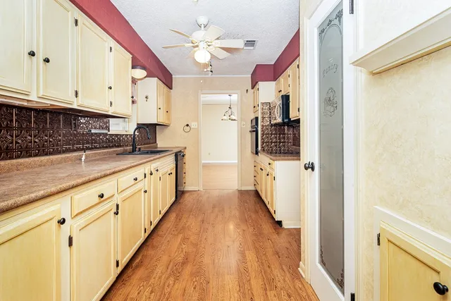 a large white kitchen with wooden floor and stainless steel appliances
