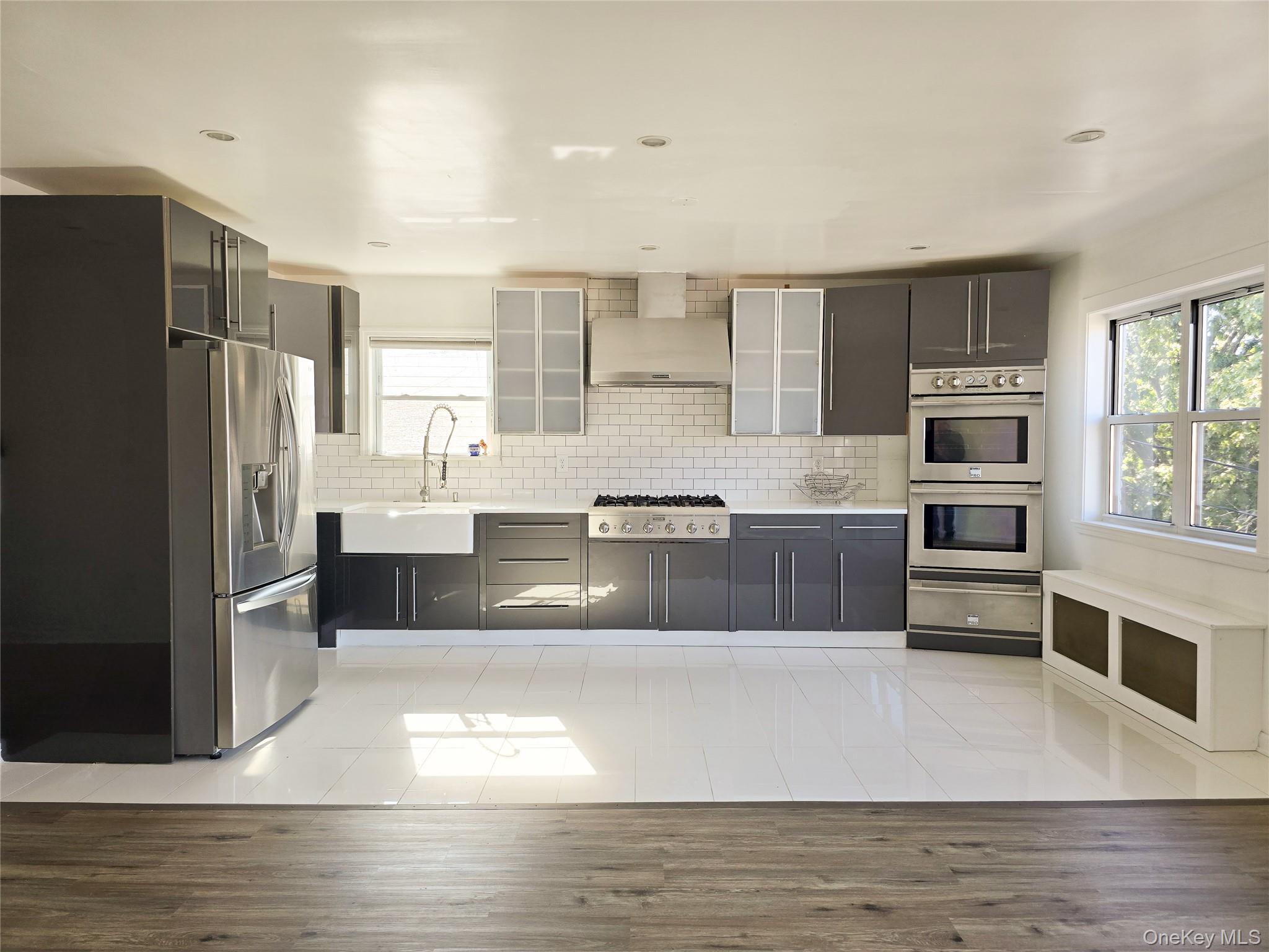 a large kitchen with stainless steel appliances a large counter top a stove and a refrigerator