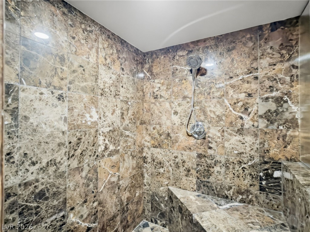 360 East Desert Inn Road, Unit 607 Las Vegas, NV 89109 - Photo 24 of 55 Indulge in this naturally illuminated shower, featuring exquisite marble tiling and a convenient built-in bench.