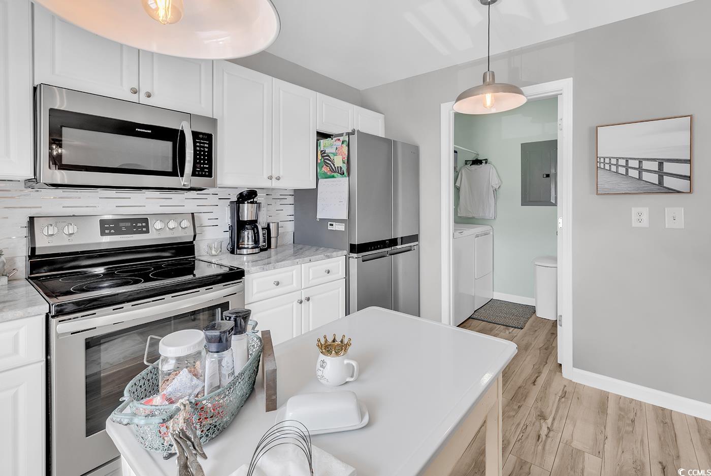 117 Butkus Drive, Unit 2 Myrtle Beach, SC 29588 - Photo 12 of 39 Kitchen with appliances with stainless steel finishes, light wood-style flooring, white cabinetry, independent washer and dryer, and decorative backsplash