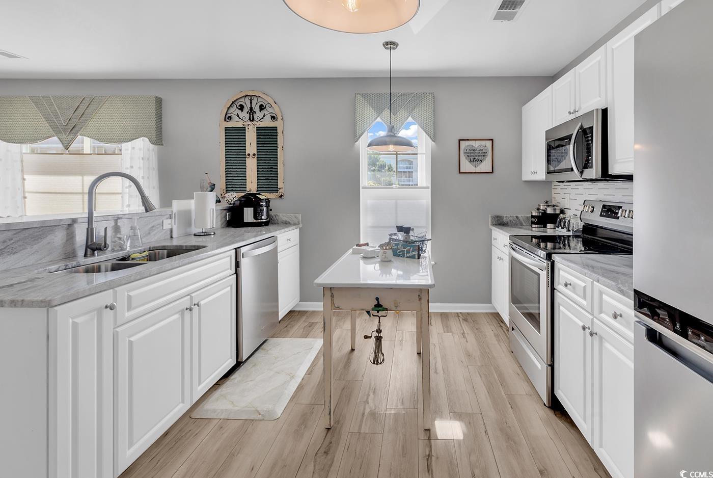 117 Butkus Drive, Unit 2 Myrtle Beach, SC 29588 - Photo 13 of 39 Kitchen with appliances with stainless steel finishes, white cabinets, light stone counters, and light wood-type flooring